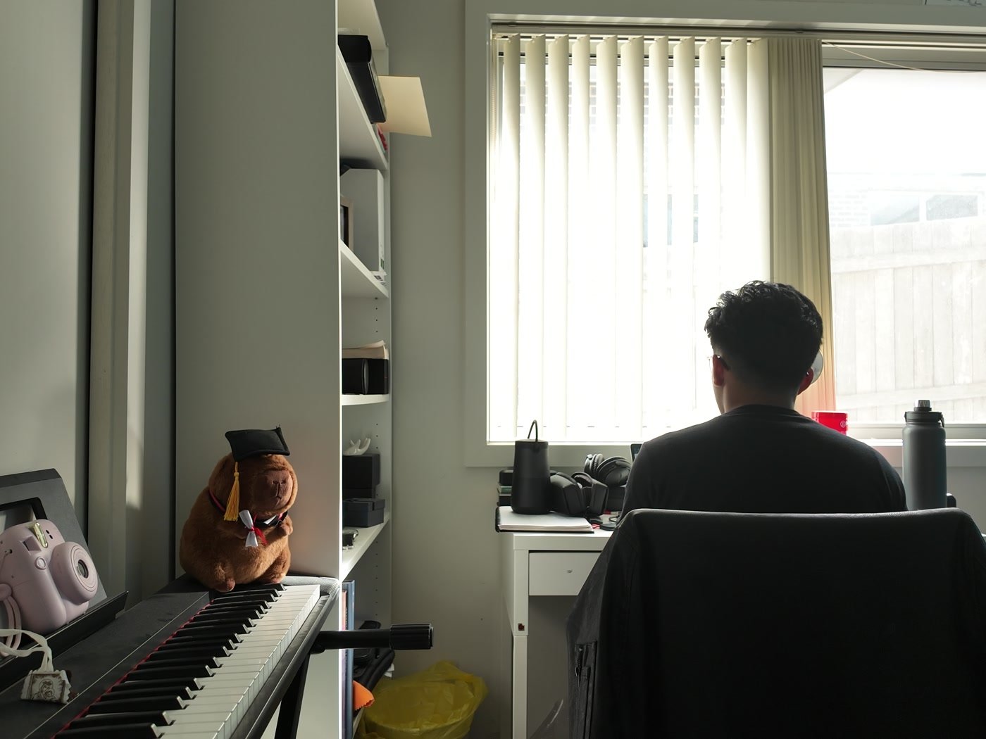 Diego working at his desk by the window, piano in the foreground